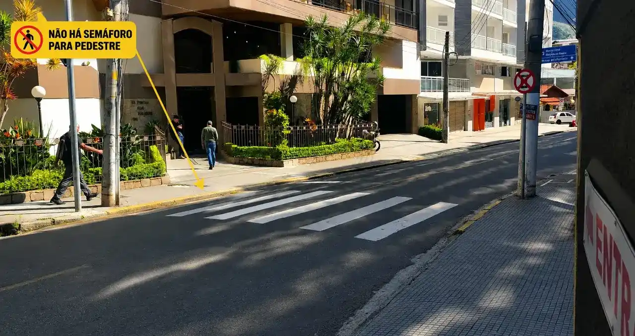 Pessoas prestam socorro a uma mulher caída na pista após atropelamento em cruzamento no Centro de Nova Friburgo.