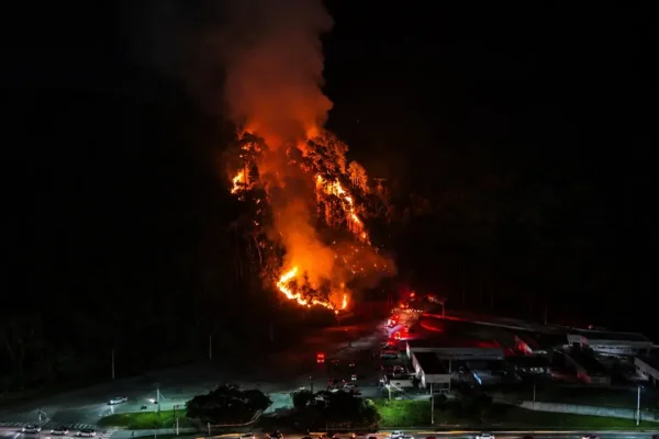 Incêndio em área de vegetação durante a noite em Olaria, Nova Friburgo, com chamas próximas a estruturas da Unidos do Imperador.