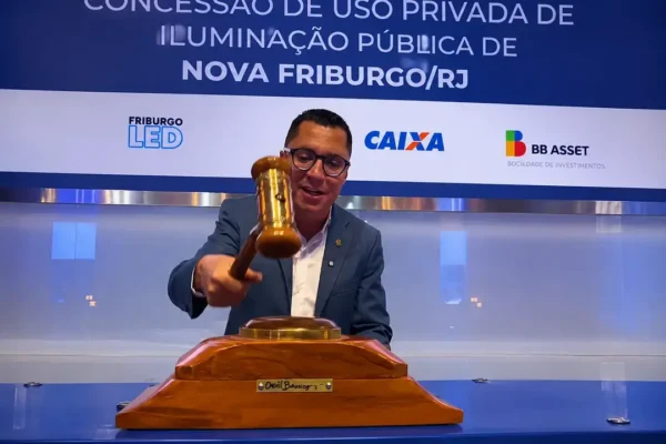 Prefeito Johnny Maycon durante anúncio da PPP de iluminação pública de Nova Friburgo, ao lado de imagem do recurso administrativo obtido pelo EcoSerrano.