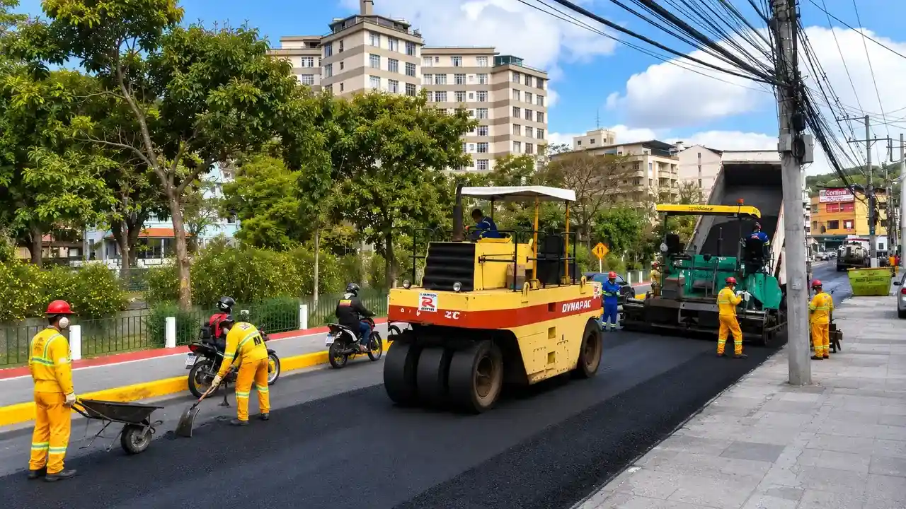Máquinas e equipes trabalham no recapeamento da RJ-116 enquanto veículos passam pelo sistema Pare e Siga no bairro Paissandu, em Nova Friburgo.