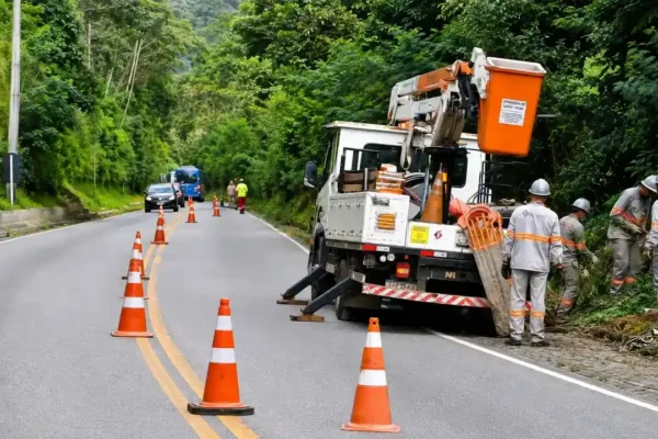 Caminhão de serviço parado às margens da RJ-116, com cones na pista e equipes trabalhando na poda de vegetação em Nova Friburgo.