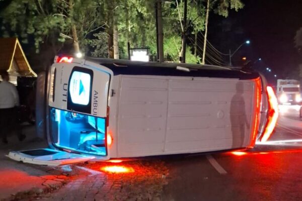 Acidente com ambulância do SAMU capotada em estrada à noite, após colisão com outros veículos.