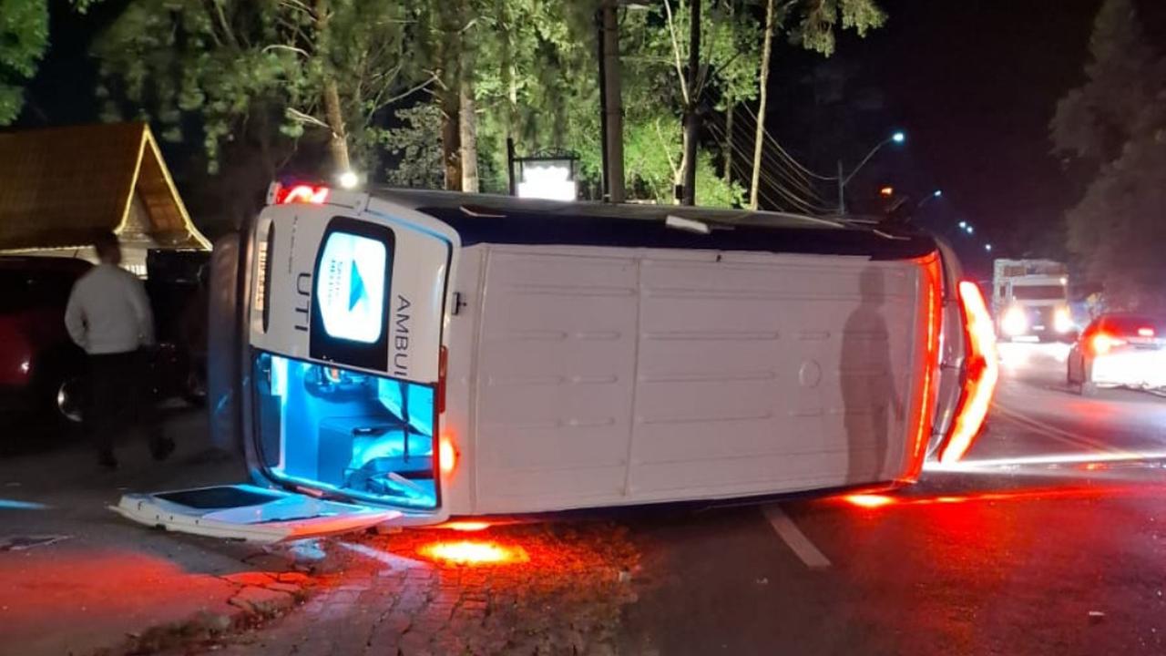 Acidente com ambulância do SAMU capotada em estrada à noite, após colisão com outros veículos.