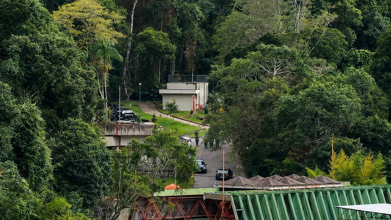 Área de mata com edifícios e veículos, possivelmente relacionada a relatos de disparos na manhã de sábado.