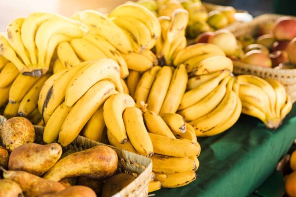 Bancada de frutas em feira: bananas, maçãs, peras e laranjas