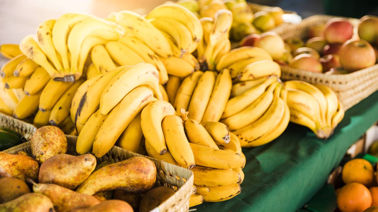 Bancada de frutas em feira: bananas, maçãs, peras e laranjas