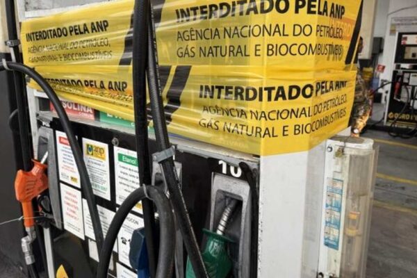 Bomba de gasolina interditada pela ANP em posto de combustível no Rio de Janeiro, com fita de interdição e texto em português.
