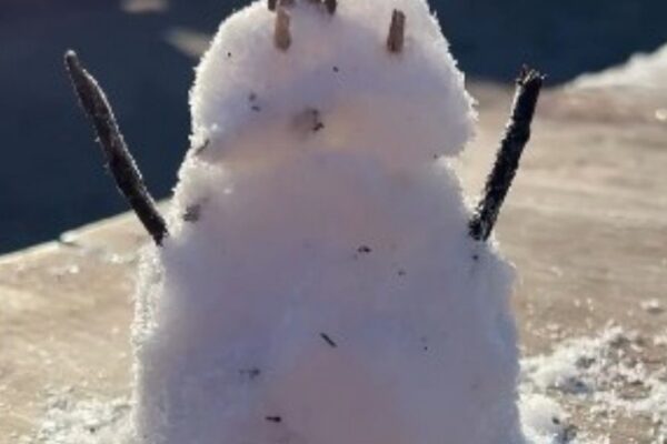 Boneco de neve simples feito na neve, com galhos como braços.
