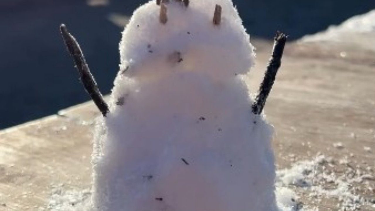Boneco de neve simples feito na neve, com galhos como braços.