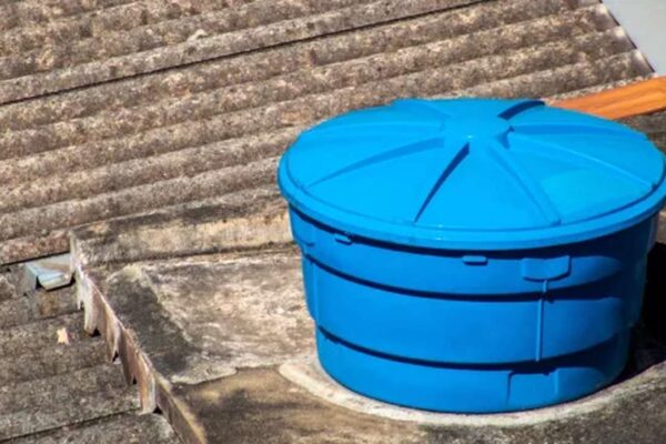 Caixa d'água azul em telhado, possivelmente no Rio de Janeiro, em contexto de problemas no abastecimento.