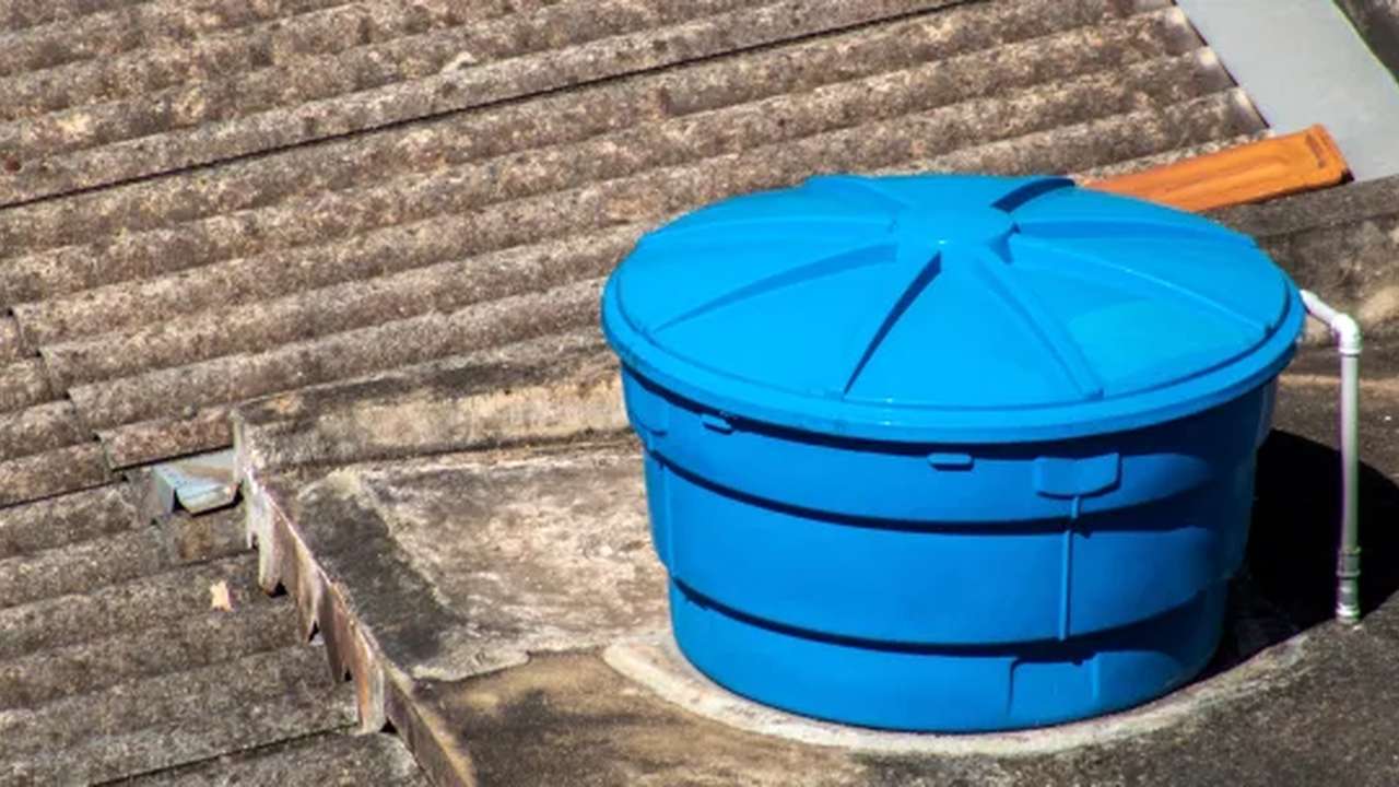 Caixa d'água azul em telhado, possivelmente no Rio de Janeiro, em contexto de problemas no abastecimento.