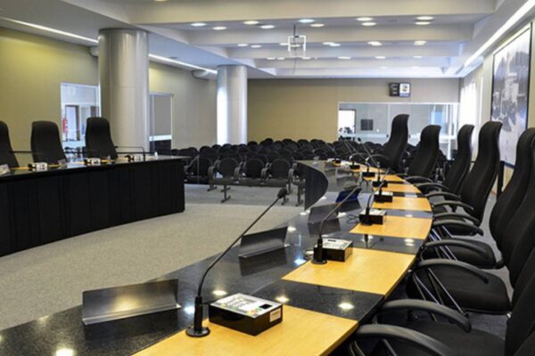 Câmara municipal com cadeiras e mesa para reuniões.