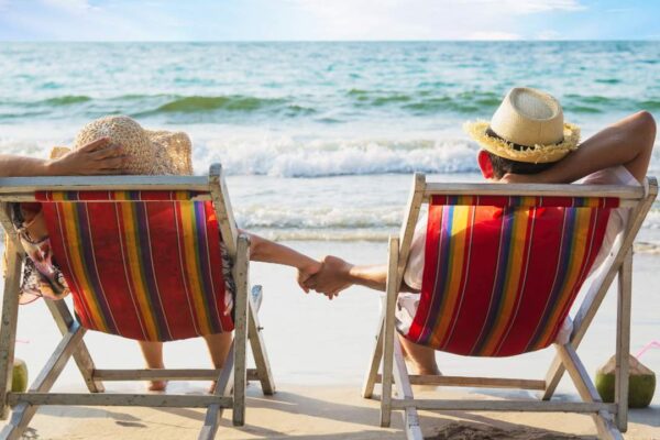 Casal relaxa em cadeiras de praia, aproveitando o feriado à beira-mar.