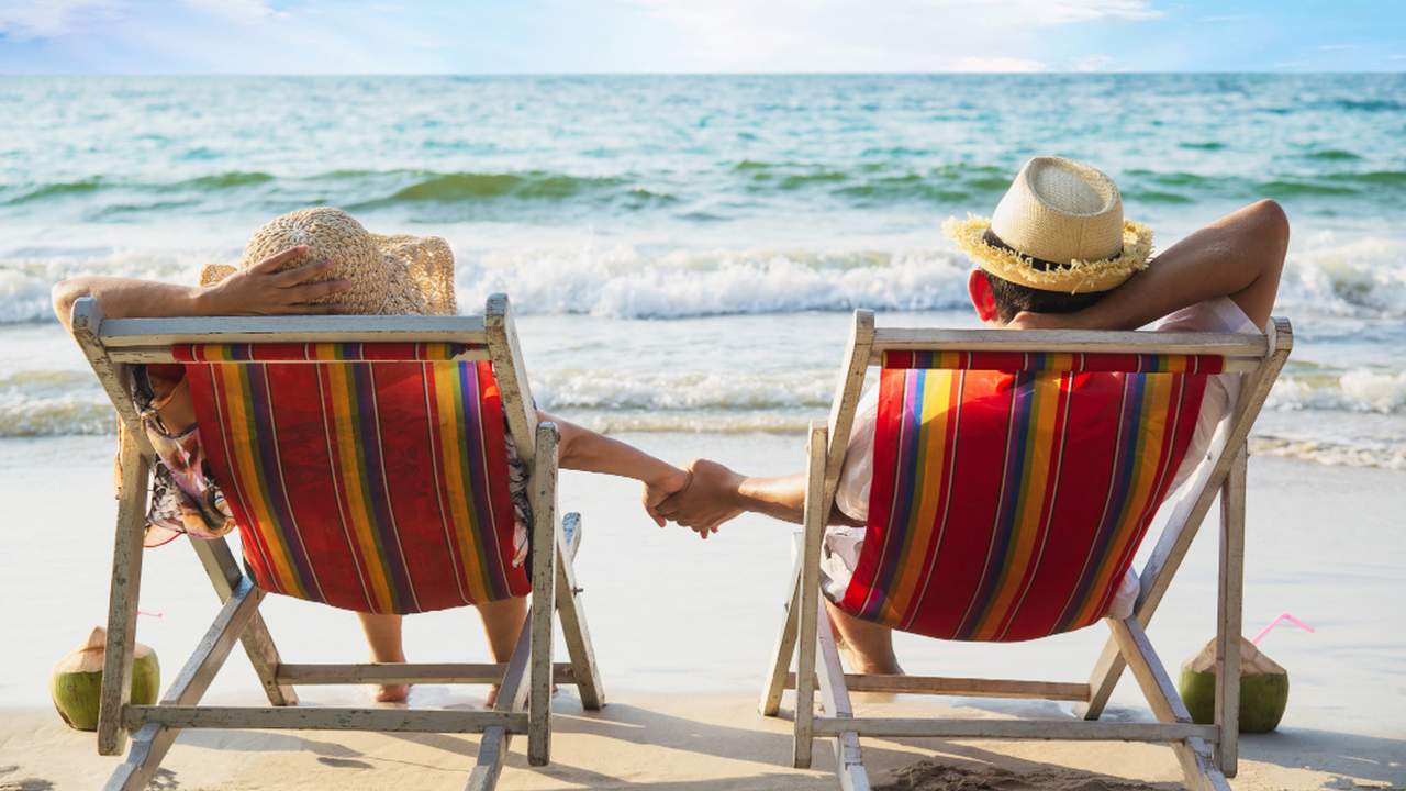 Casal relaxa em cadeiras de praia, aproveitando o feriado à beira-mar.