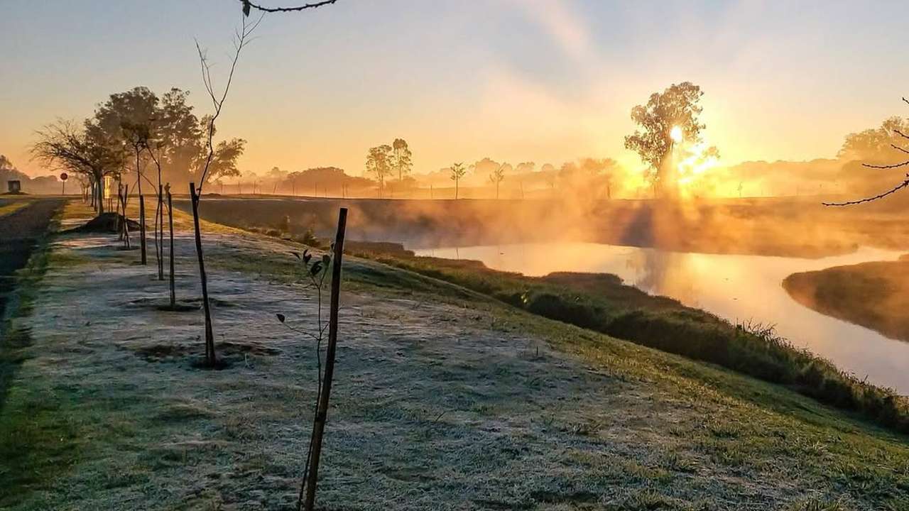 Cenário de geada e amanhecer frio no Rio de Janeiro, com árvores e rio.