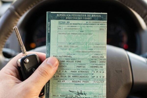 Certificado de Registro e Licenciamento de Veículo (CRLV) em mãos, com chave de carro.
