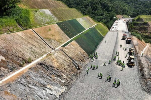 Construção de estrada em encosta com operários e máquinas