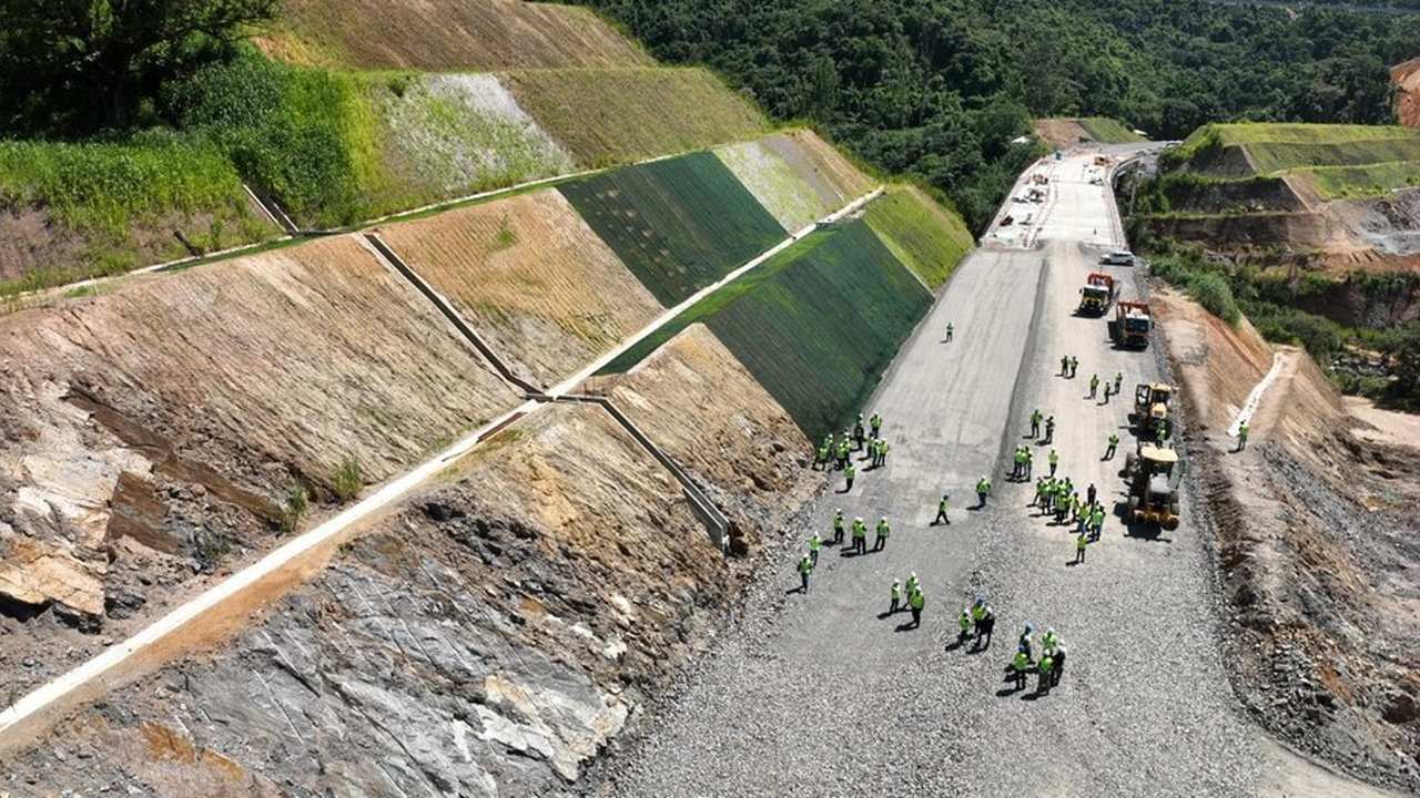 Construção de estrada em encosta com operários e máquinas