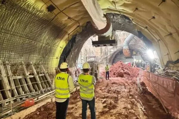 Construção de túnel do metrô em São Paulo com trabalhadores e estruturas metálicas.