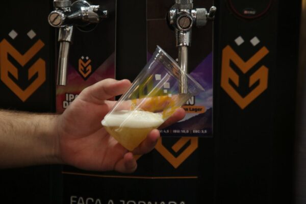 Copo de cerveja sendo servido em evento de cervejas artesanais. Foco na espuma e no líquido.