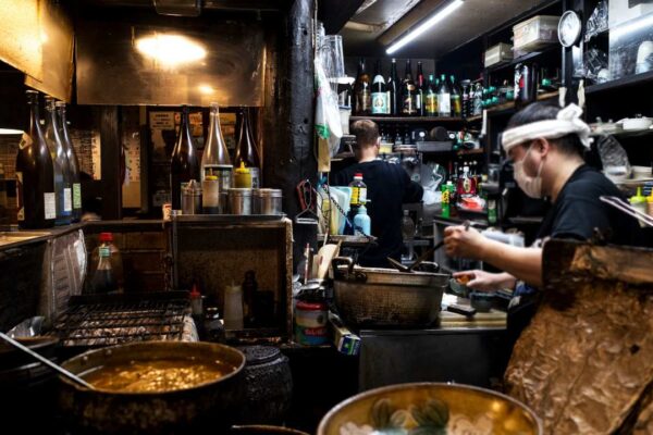 Cozinha de restaurante com trabalhadores preparando alimentos.