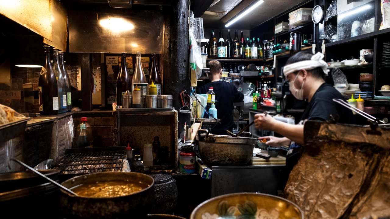 Cozinha de restaurante com trabalhadores preparando alimentos.