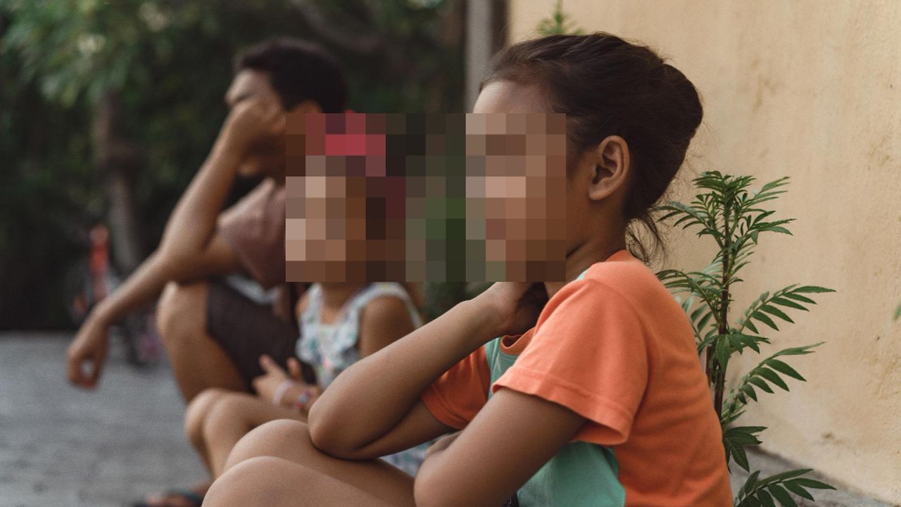 Crianças e adulto sentados, imagem pixelada, contexto de problemas estruturais e excesso de acolhidos.
