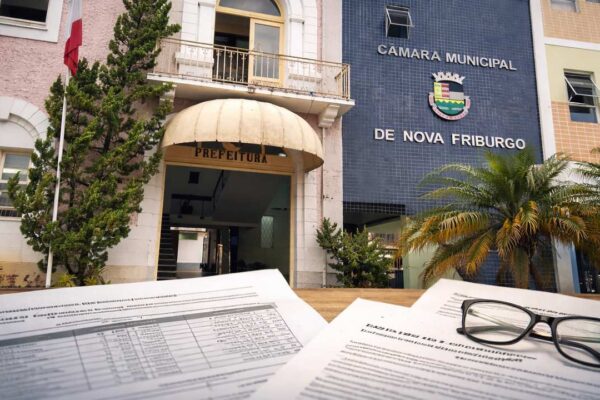 Documentos e óculos sobrepostos a prédios em Nova Friburgo, RJ.