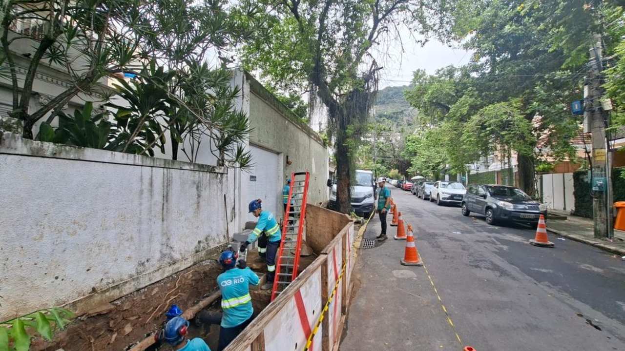 Equipe da concessionária CG Rio realiza manutenção em rua, com vala aberta e cones de sinalização.