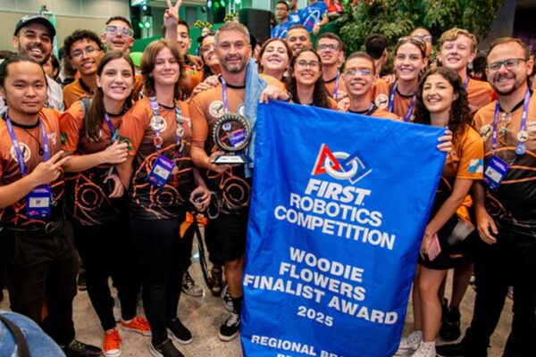 Equipe de robótica de Nova Friburgo celebra no torneio em São Paulo, com troféu e banner.