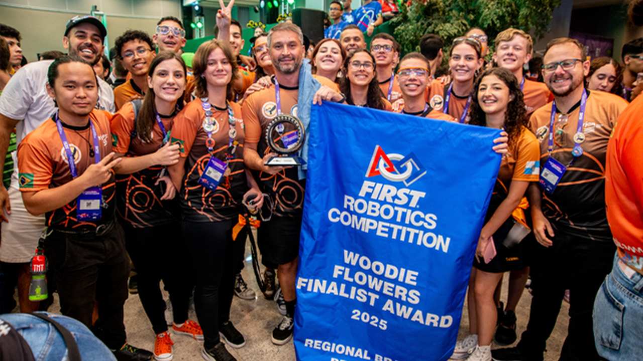 Equipe de robótica de Nova Friburgo celebra no torneio em São Paulo, com troféu e banner.