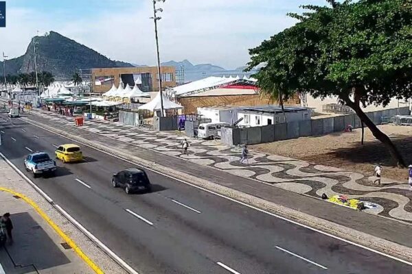 Avenida Brasil com faixa interditada e central de monitoramento exibindo imagens de áreas movimentadas do Rio.