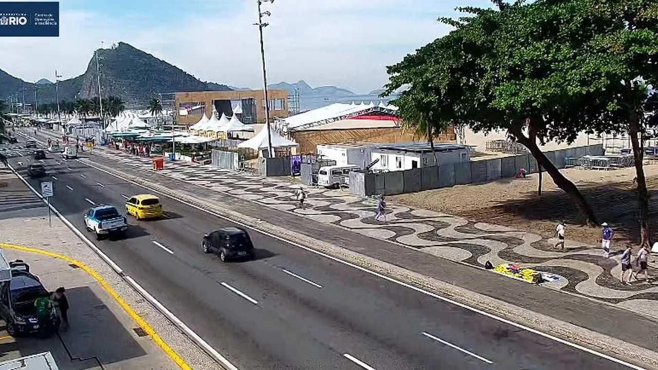 Avenida Brasil com faixa interditada e central de monitoramento exibindo imagens de áreas movimentadas do Rio.