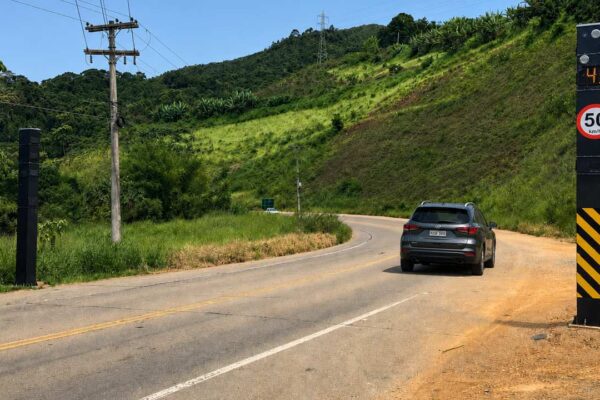 Radar de fiscalização instalado às margens da RJ-106 enquanto veículos trafegam pela Rodovia Amaral Peixoto.