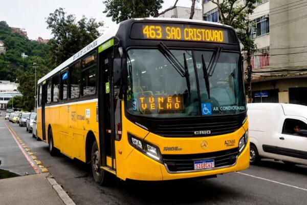 Ônibus novo do Sistema RIO circulando em via urbana, representando a retomada da linha entre São Cristóvão e Copacabana.