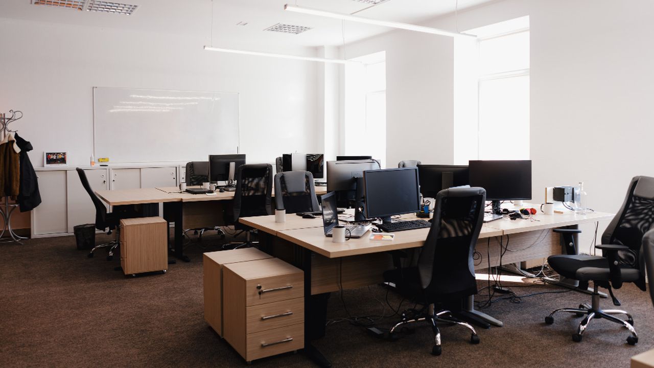 Escritório moderno com computadores e estações de trabalho.