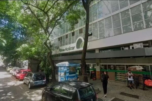 Fachada do Pão de Açúcar em Botafogo, Rio de Janeiro, com carros estacionados e árvores.
