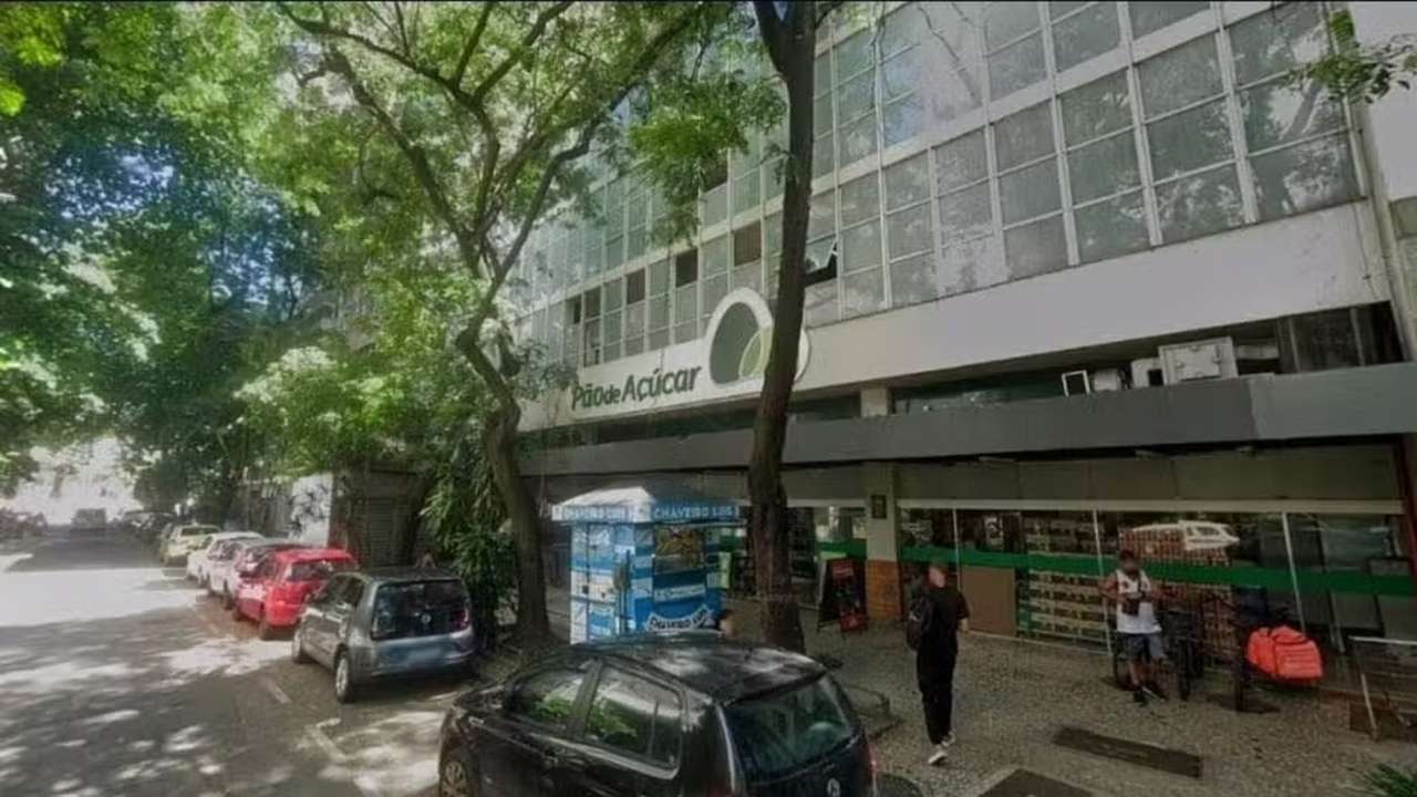 Fachada do Pão de Açúcar em Botafogo, Rio de Janeiro, com carros estacionados e árvores.