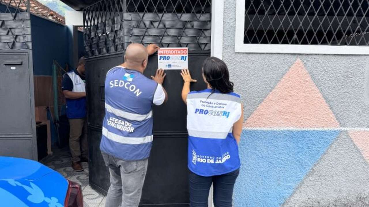 Fiscalização do Procon-RJ em estabelecimento, com sinalização de interdição. Agentes colam aviso na porta.