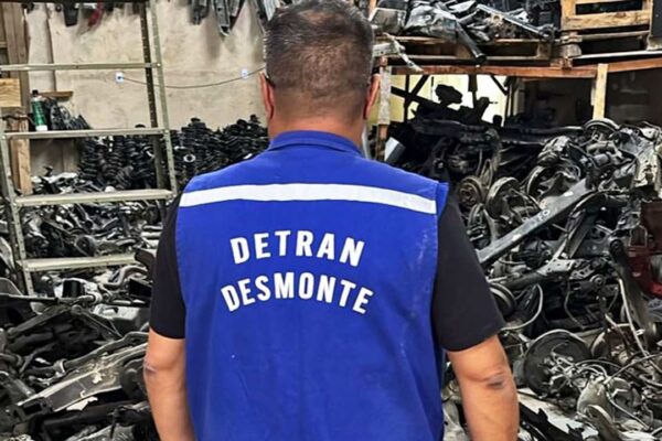 Homem com colete do Detran em galpão de peças automotivas irregulares.