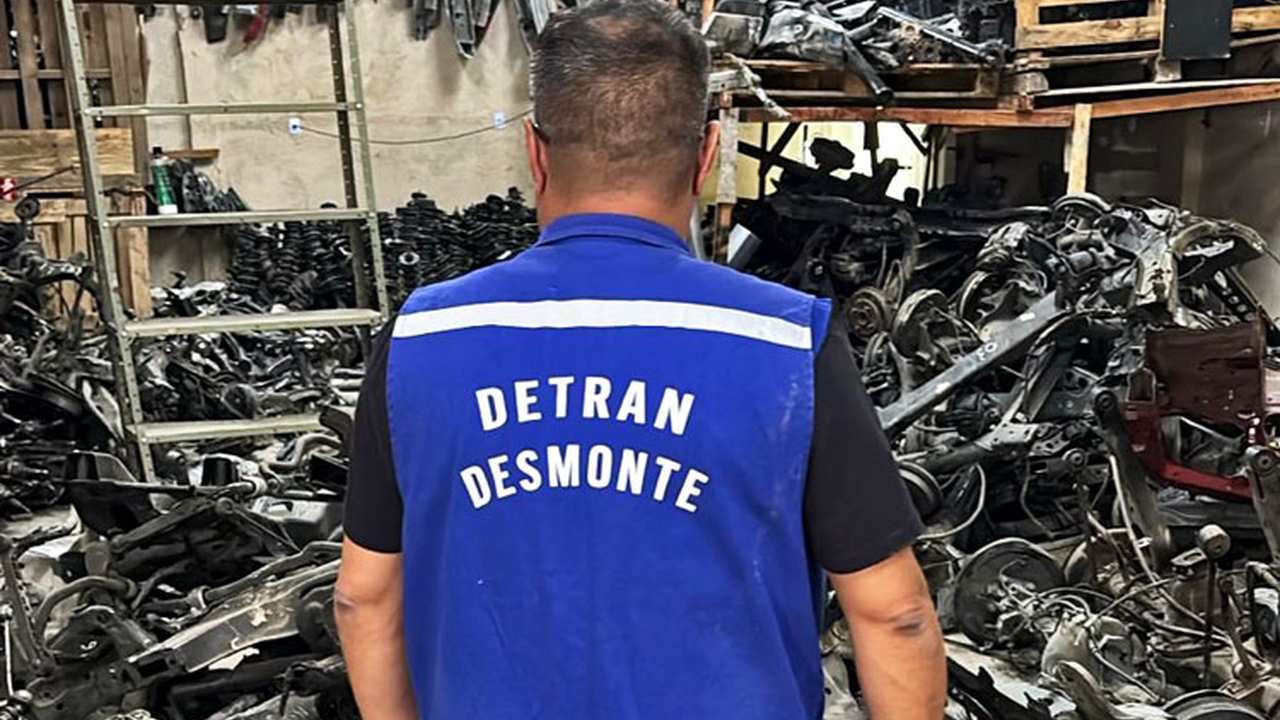 Homem com colete do Detran em galpão de peças automotivas irregulares.