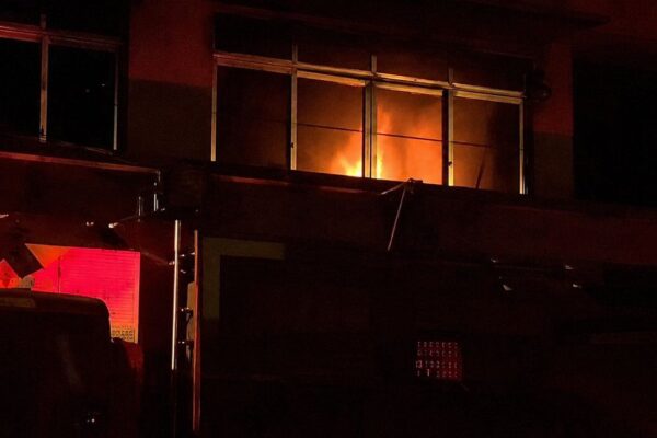 Incêndio em padaria em Nova Friburgo, bairro Olaria, com chamas visíveis em janela.