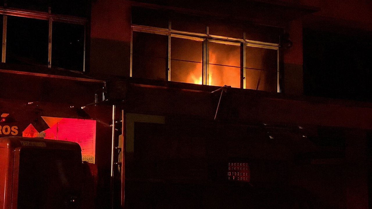 Incêndio em padaria em Nova Friburgo, bairro Olaria, com chamas visíveis em janela.