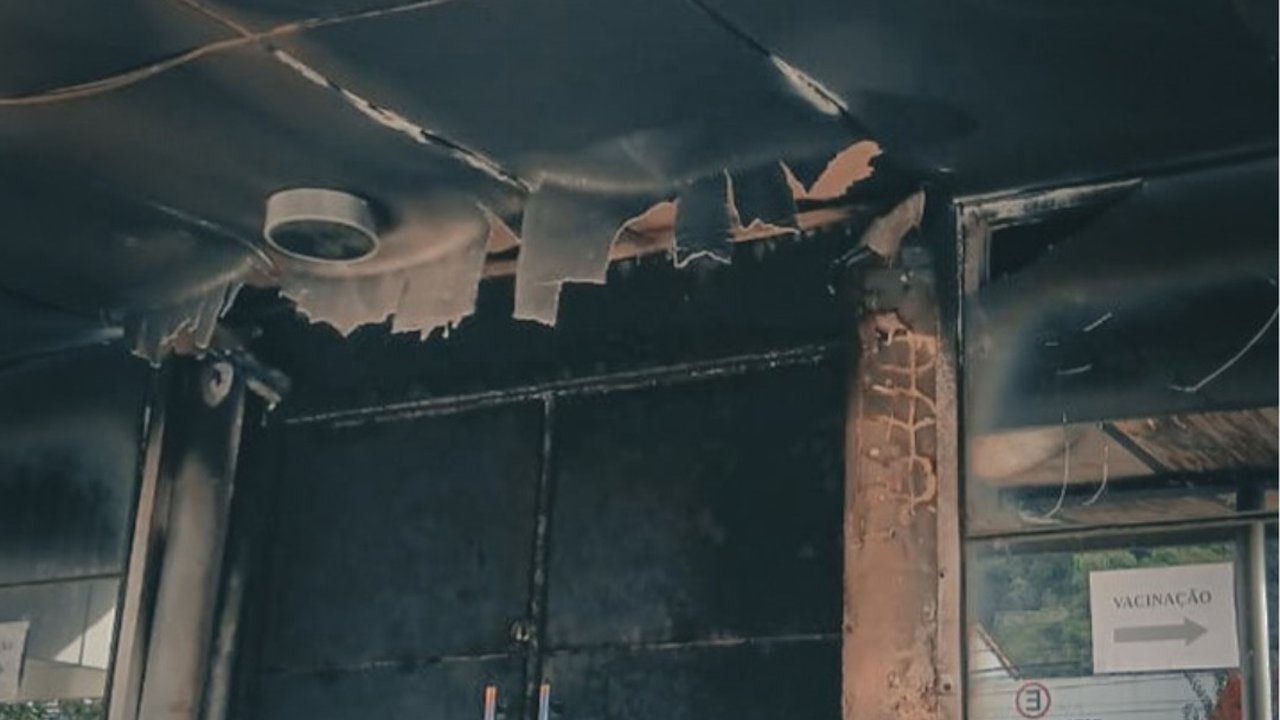 Interior de posto de saúde danificado por incêndio criminoso, com teto e estrutura destruídos.