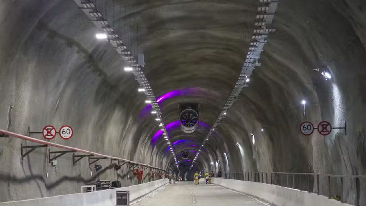 Interior de túnel rodoviário com iluminação e sinalização. Sinalização de velocidade 60 km/h.