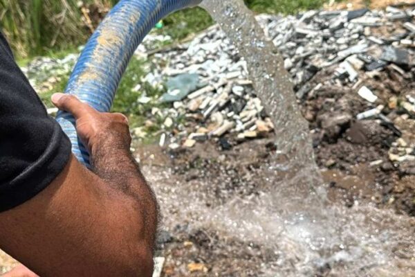 Mangueira de água sendo utilizada em área afetada por falta de abastecimento.