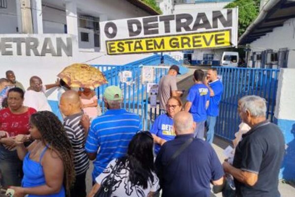 Manifestação em frente ao Detran com placa 'O Detran está em greve'.
