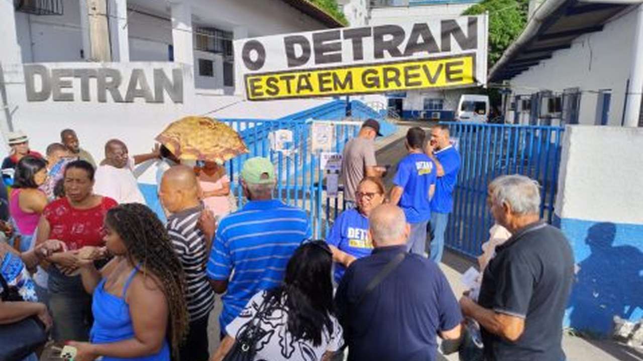 Manifestação em frente ao Detran com placa 'O Detran está em greve'.