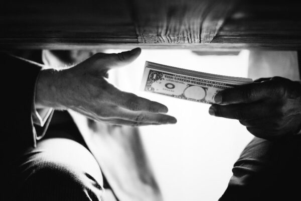 Mãos trocando dinheiro, em uma cena que pode sugerir corrupção.