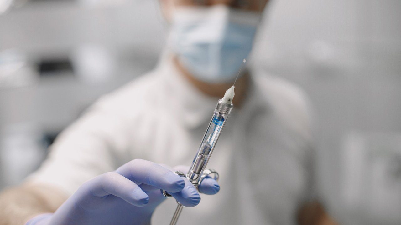 Médico com seringa em hospital, contexto de ação judicial por improbidade.